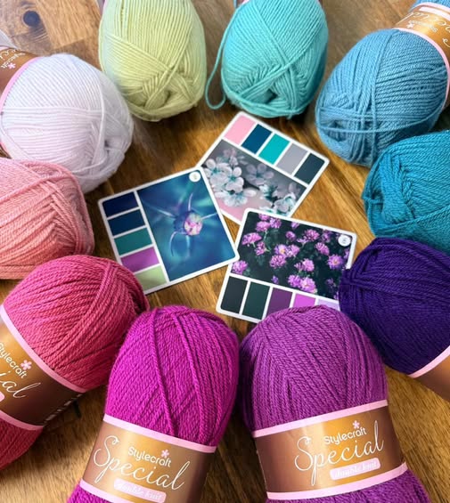 Colourful Stylecraft DK balls of yarn on a wooden surface with colour swatches.